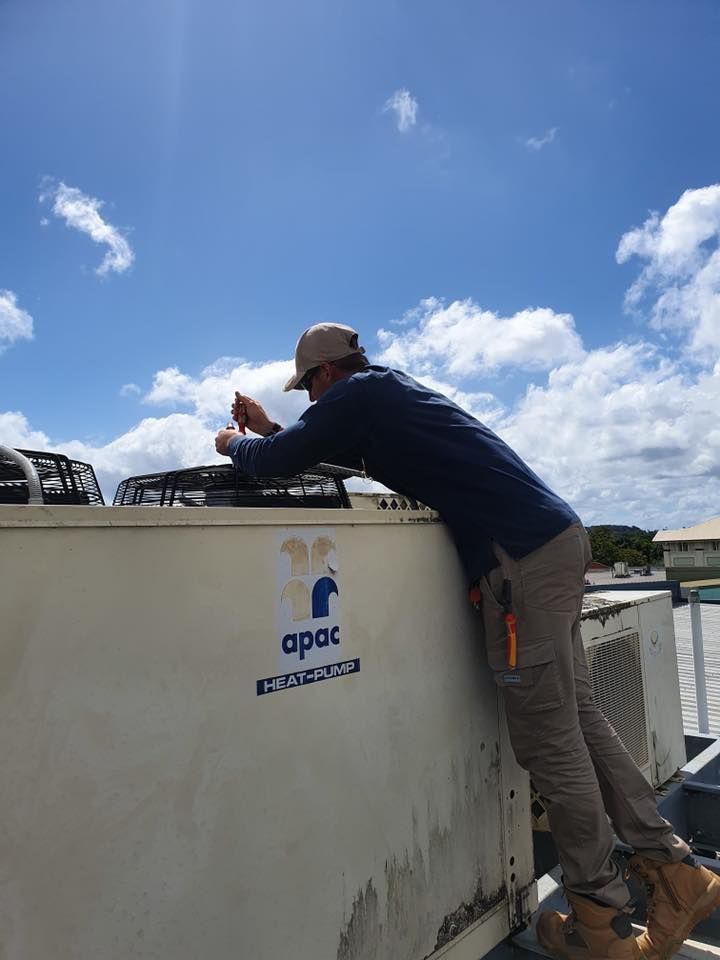A Person in Work Attire Repairs an Air Conditioning Unit — Don Hall Air Conditioning & Electrical in Mareeba, QLD