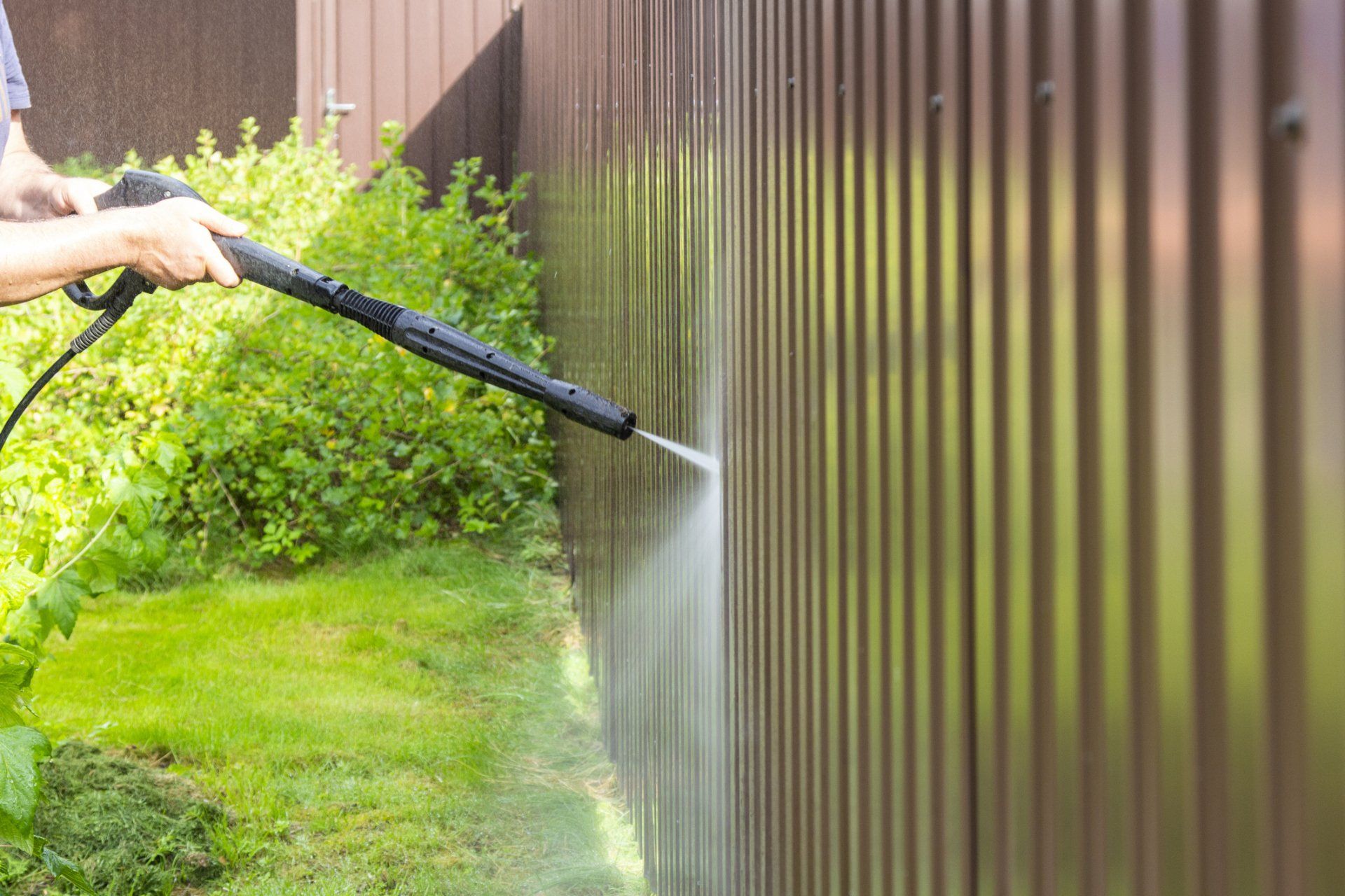 image of man power washing wooden patio