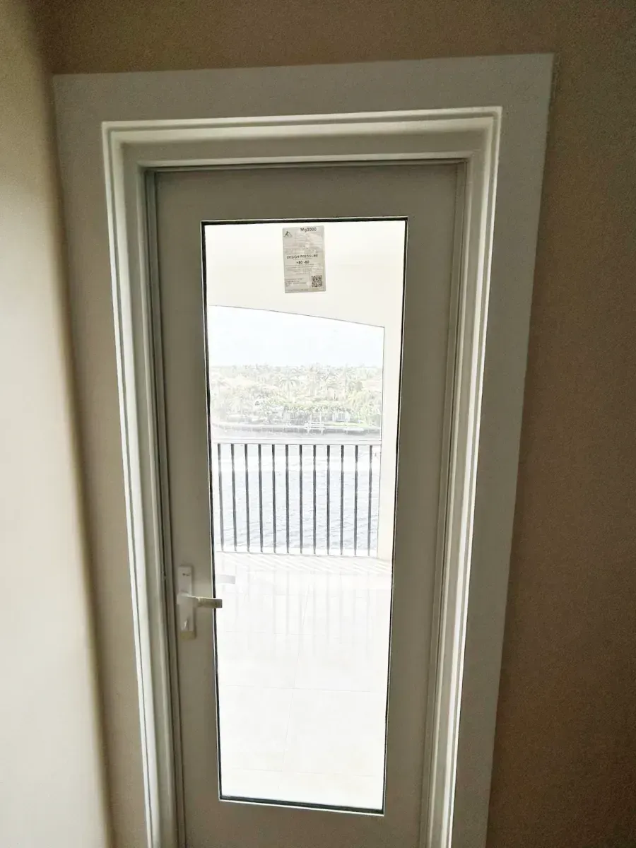 A light gray exterior door with a glass panel, set in a matching frame, looking out onto a wooden deck and railing.
