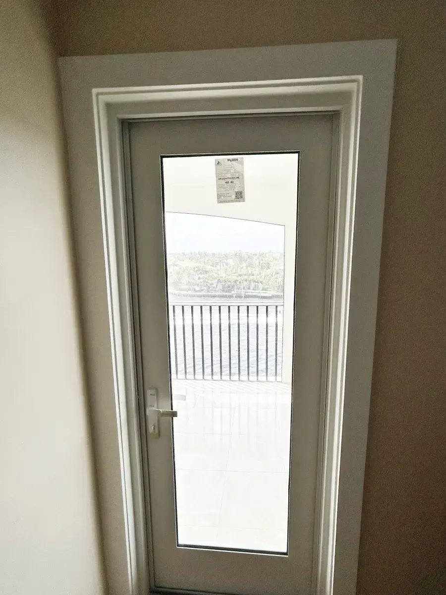 A gray door with a full-length glass panel and white trim, viewed from inside a room with light-colored walls.