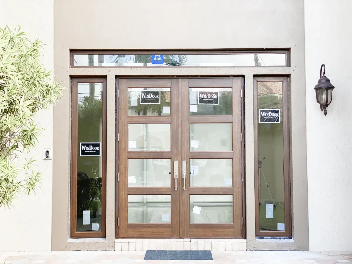 A front entrance featuring double wood-framed doors with four glass panels each, flanked by narrow glass sidelights.