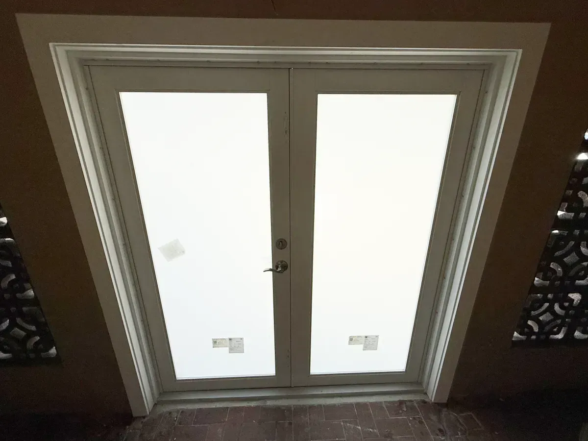 White double doors with frosted glass panels set in a tan-colored wall.