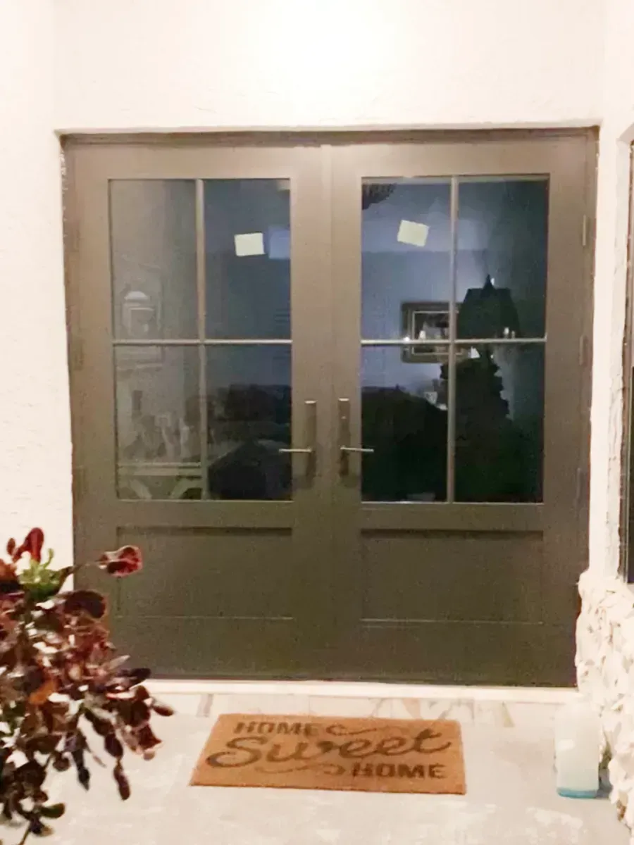 A dark-framed double entry door with four glass panes each, featuring a 