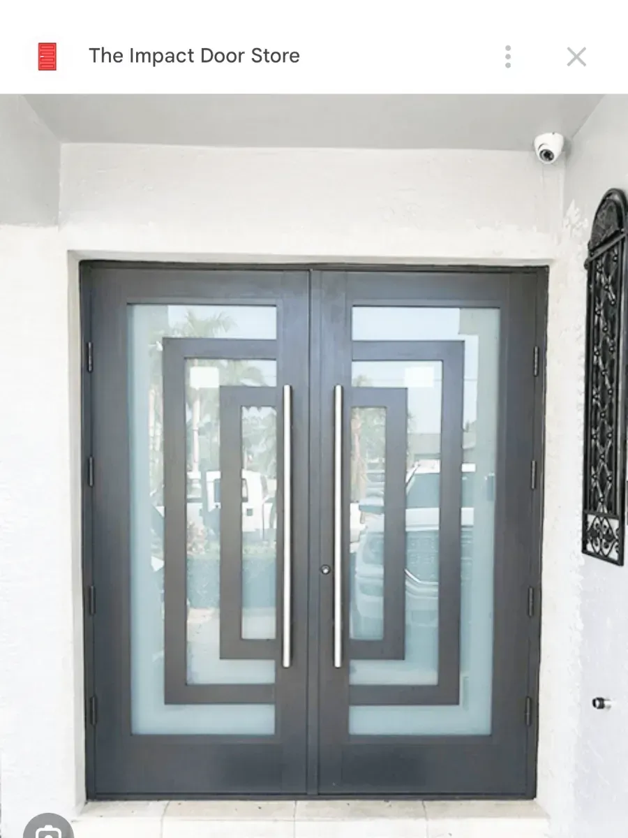 A dark double entry door with rectangular frosted glass inlays and long, vertical silver handles.