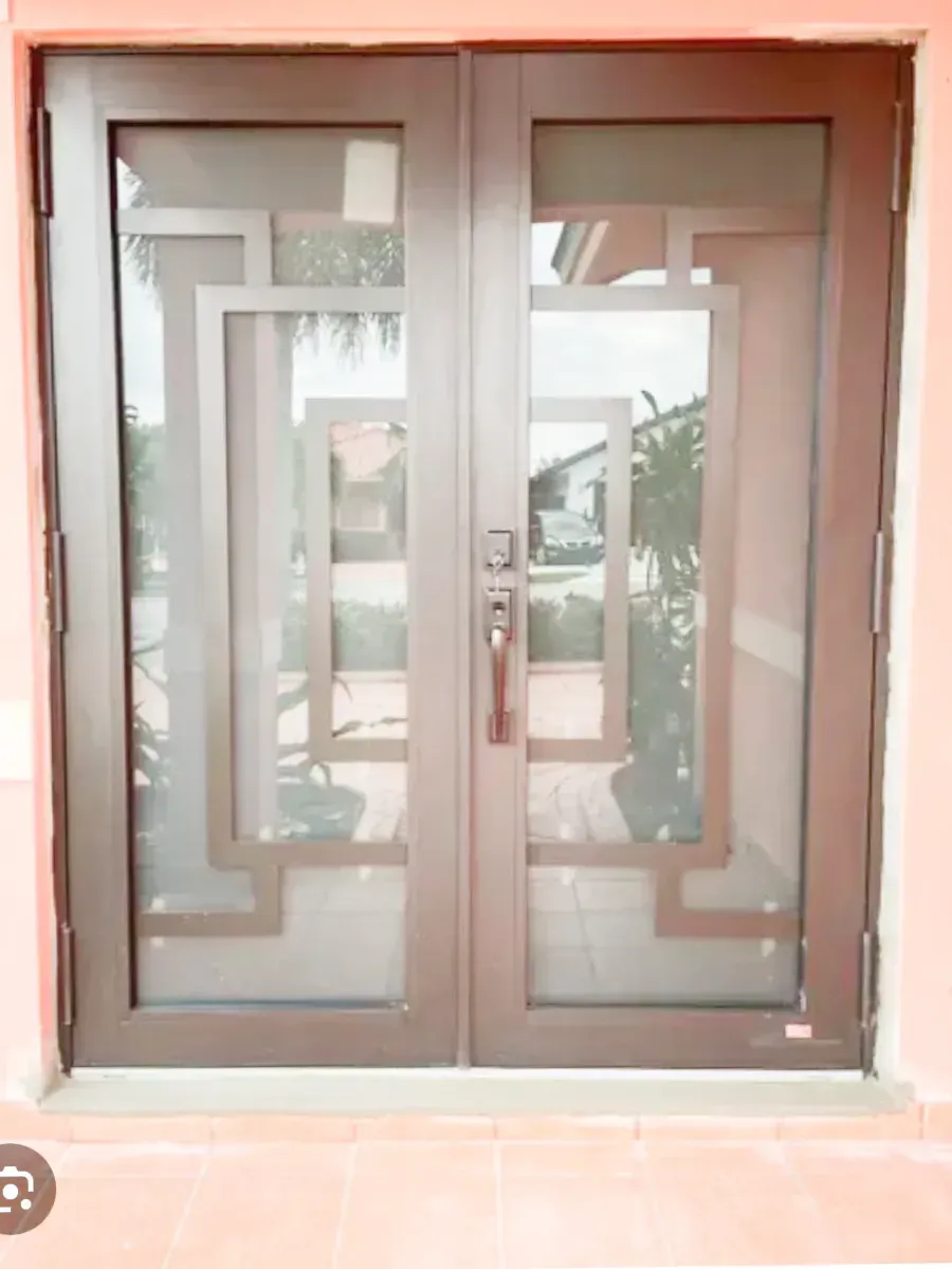 Brown double doors with decorative rectangular patterns and glass panels set in a light-colored frame.