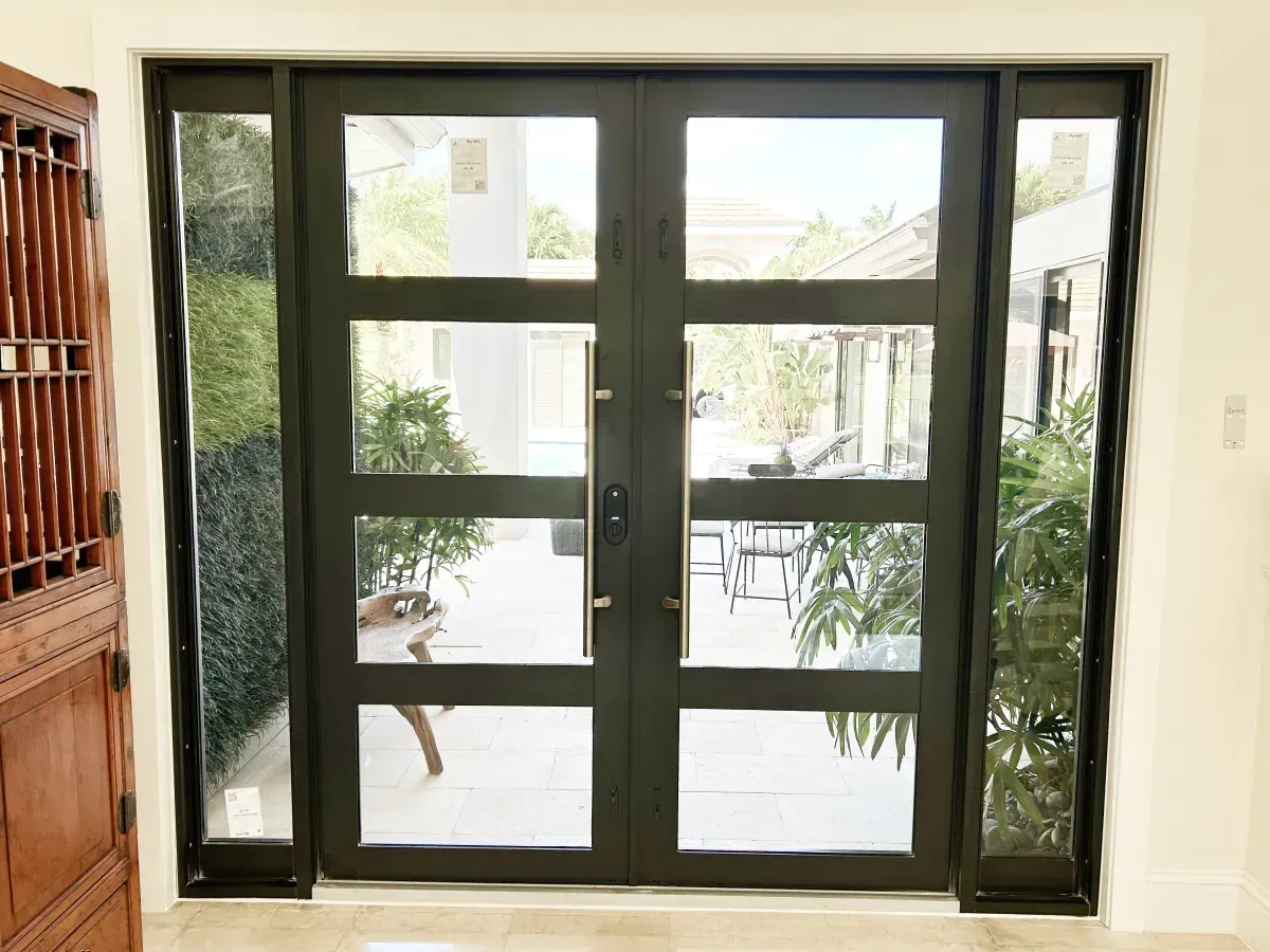 Black double front doors with four horizontal glass panes each, flanked by narrow vertical glass sidelights.