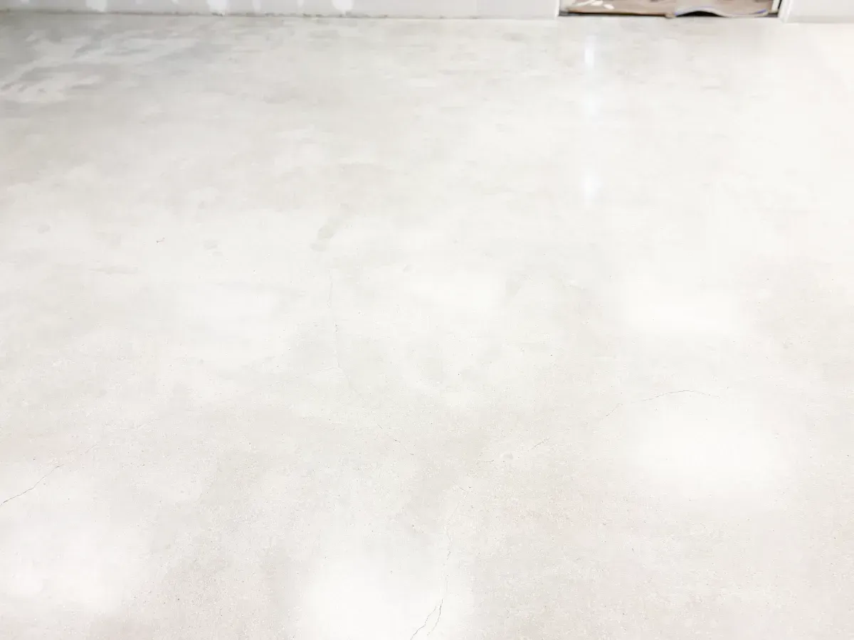A polished, light-gray concrete floor surface in a room with unfinished drywall walls.