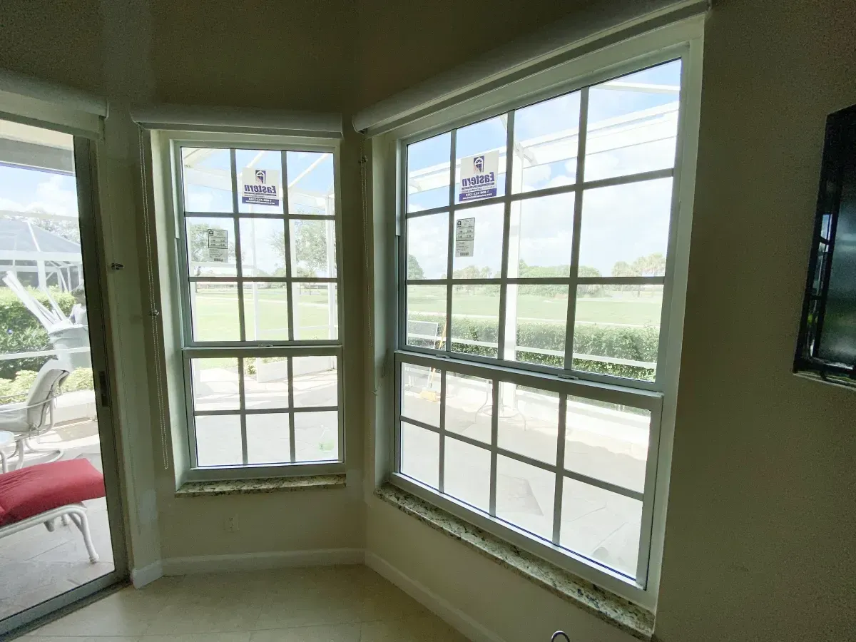 A corner featuring two large windows with grid muntins, looking out onto a grassy landscape and a patio with furniture.
