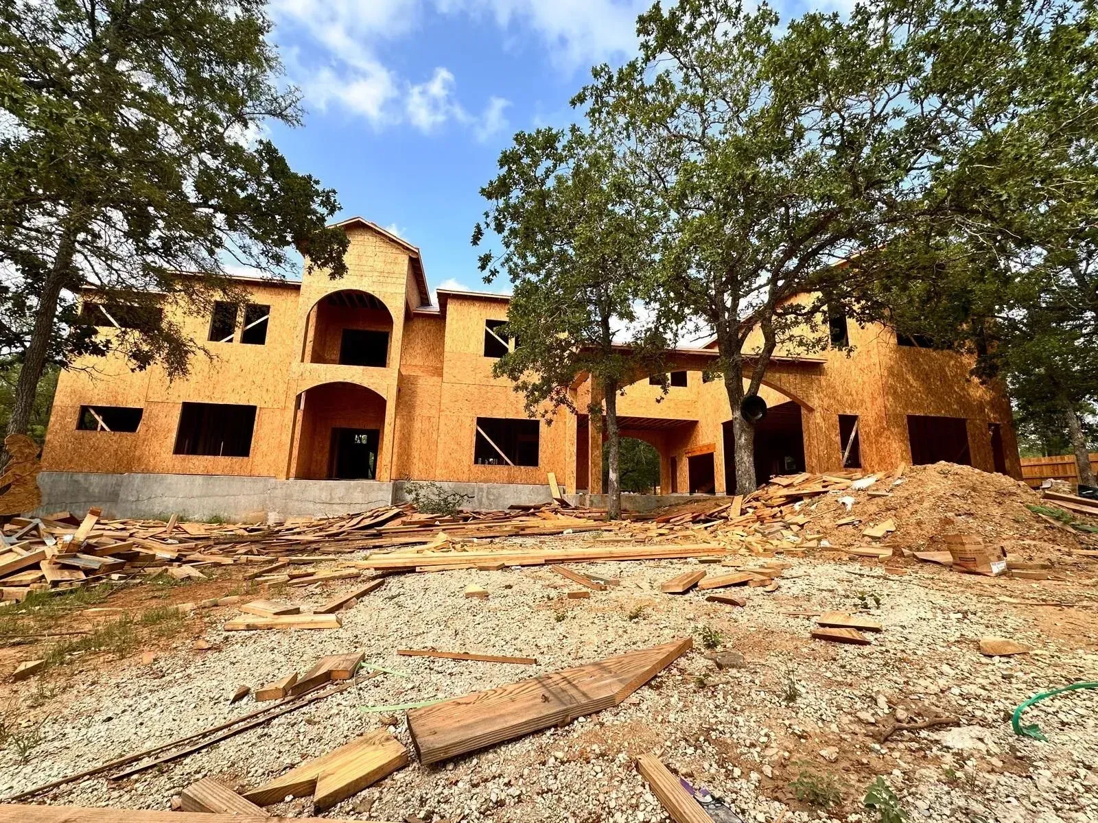 A large house is being built in the middle of a dirt field.