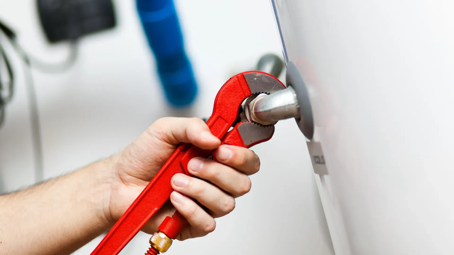 A person is fixing a water heater with a wrench.