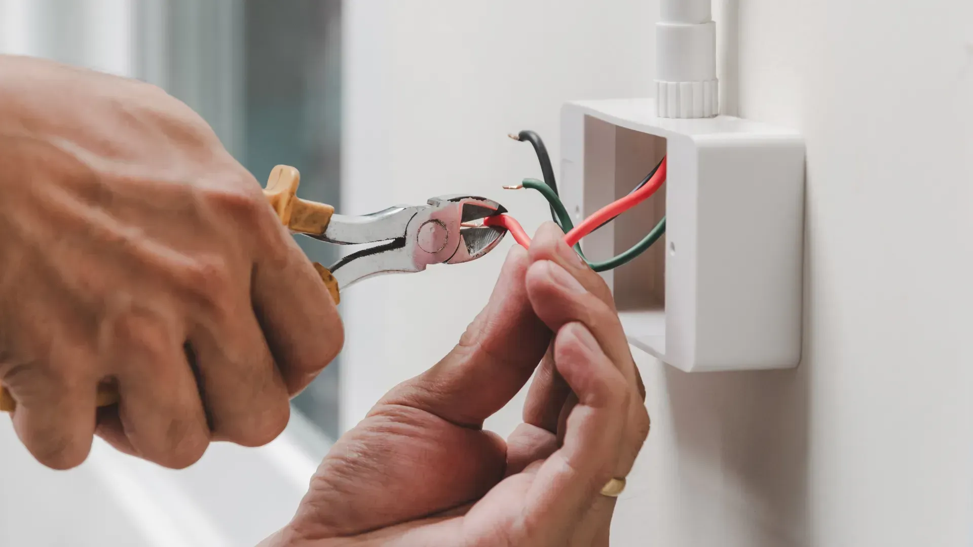 A person is working on an electrical box on a wall.