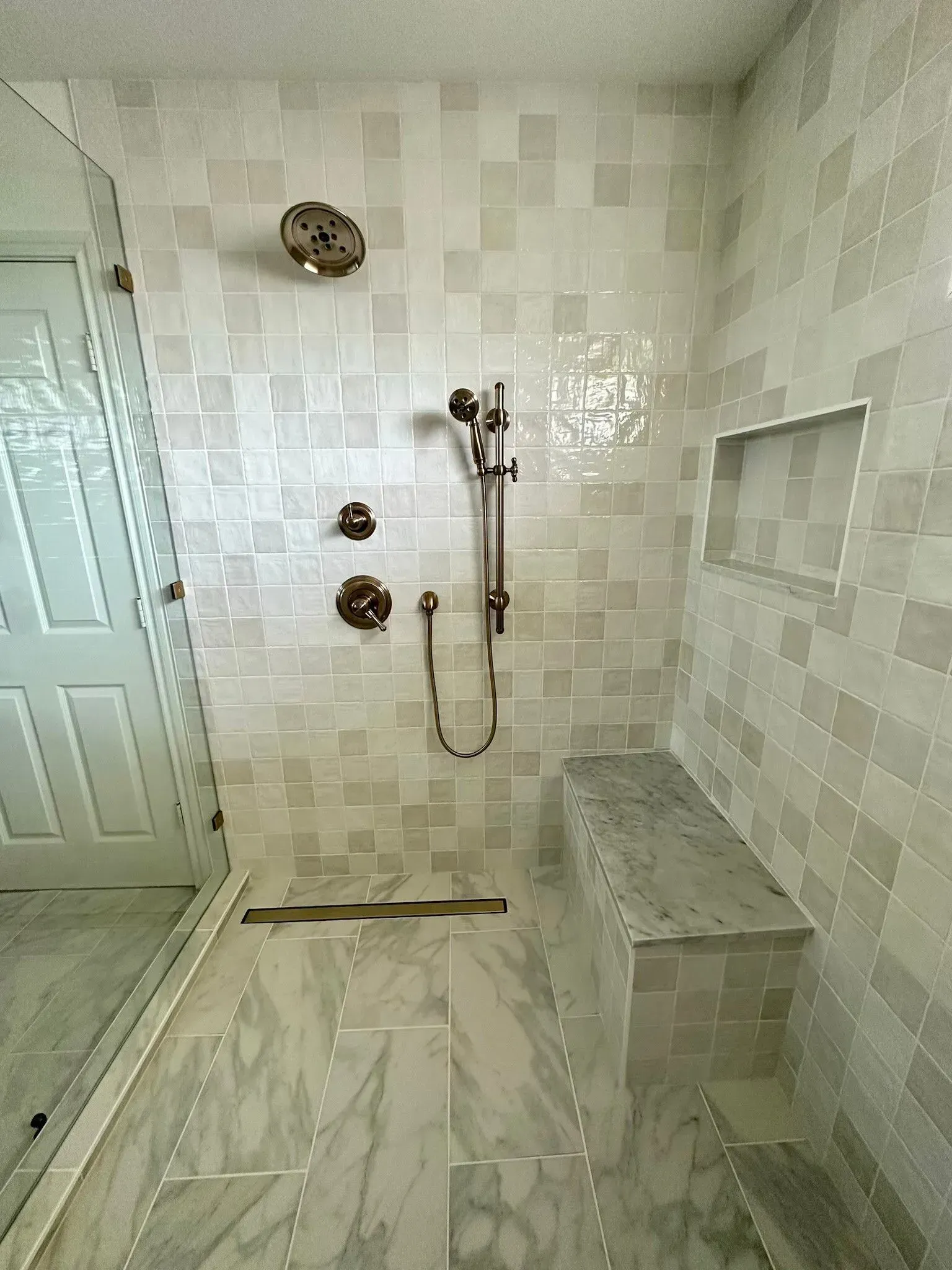 A bathroom with a walk in shower and a bench.