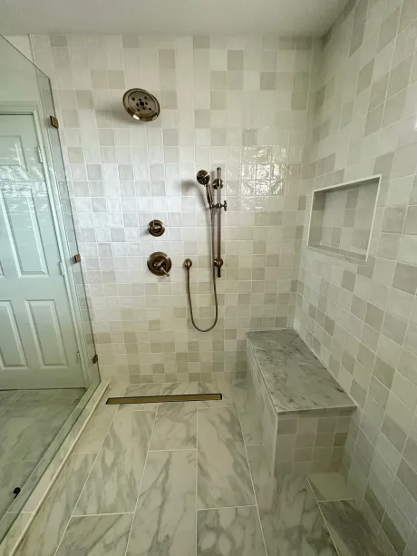 A bathroom with a walk in shower and a bench.