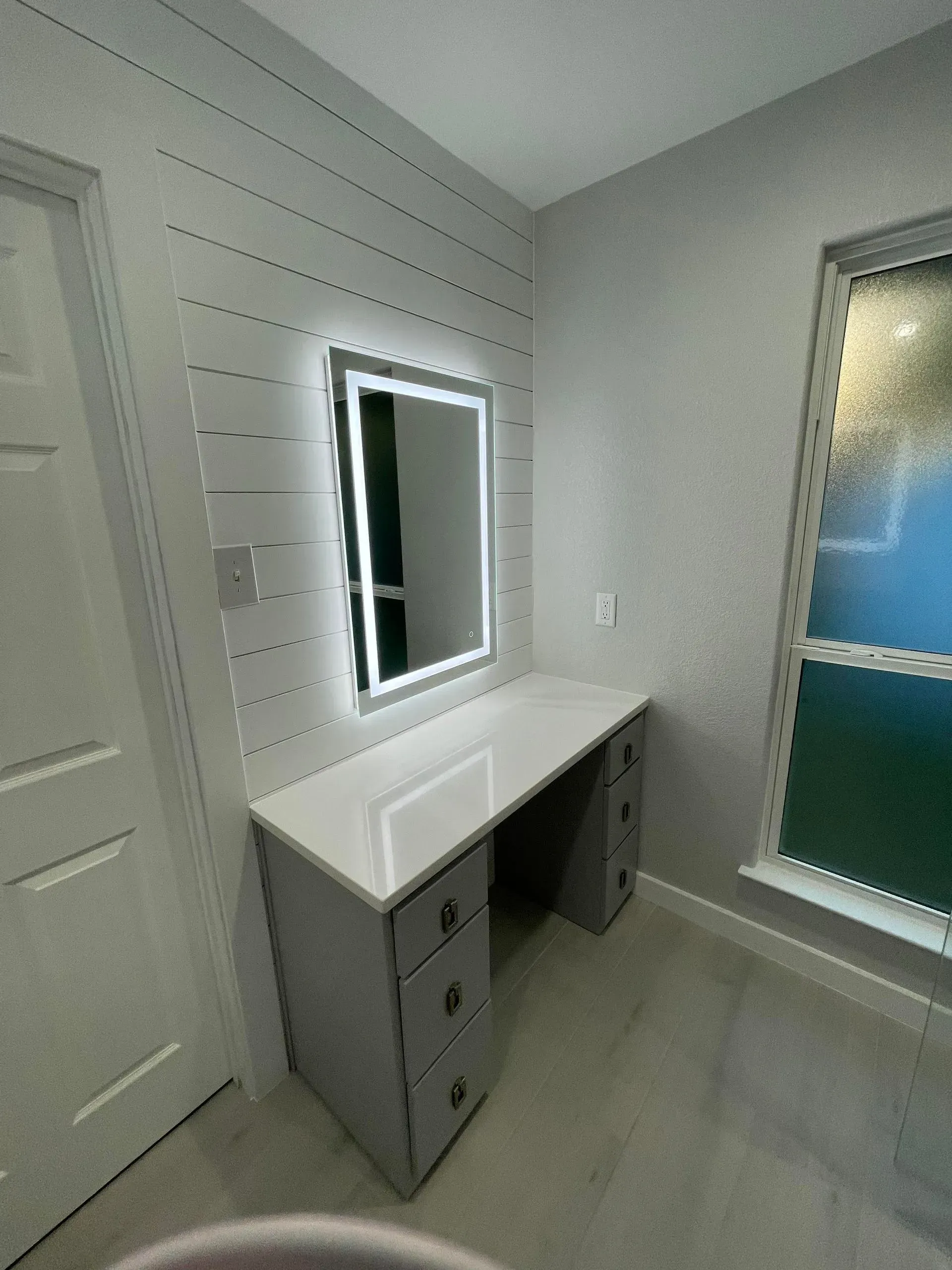 A room with a desk and a mirror on the wall.