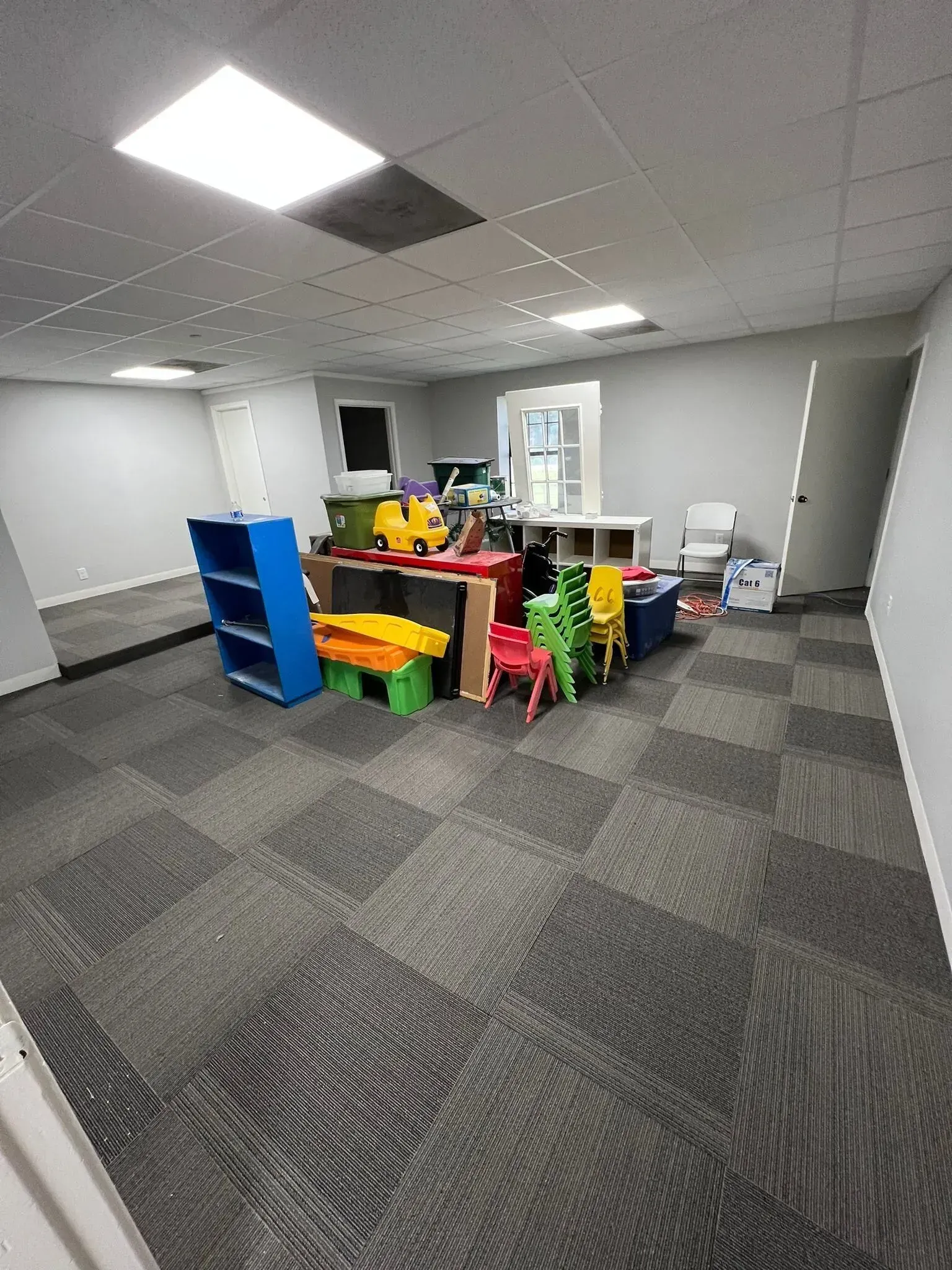 A room with a lot of toys on the floor and a table and chairs.