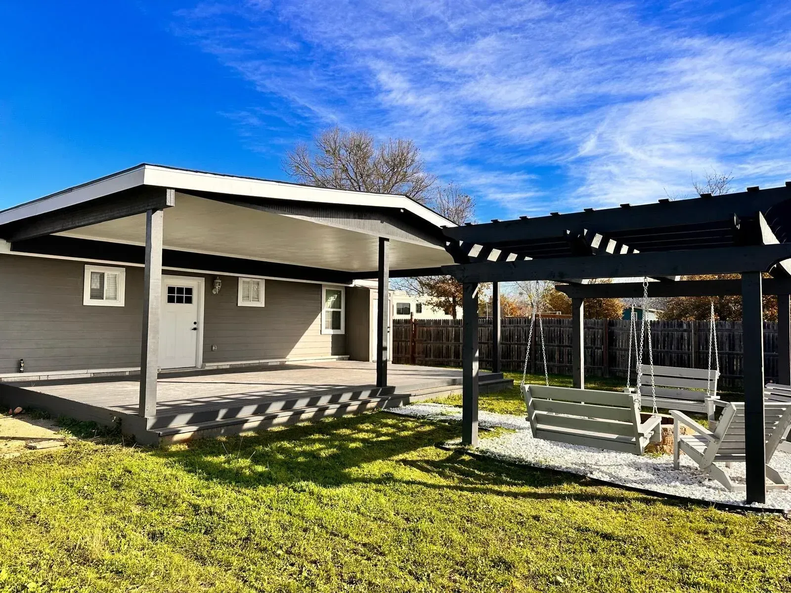 A house with a carport and a swing in the backyard.