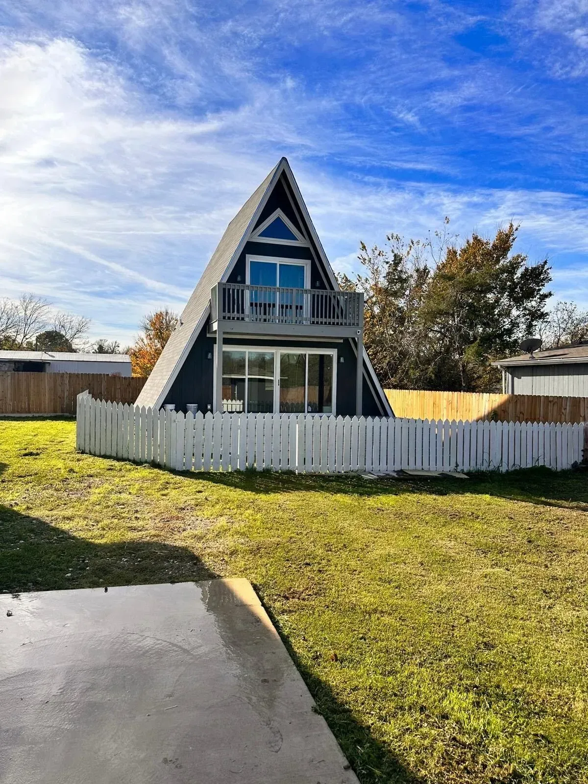 A small a frame house with a white picket fence in front of it.