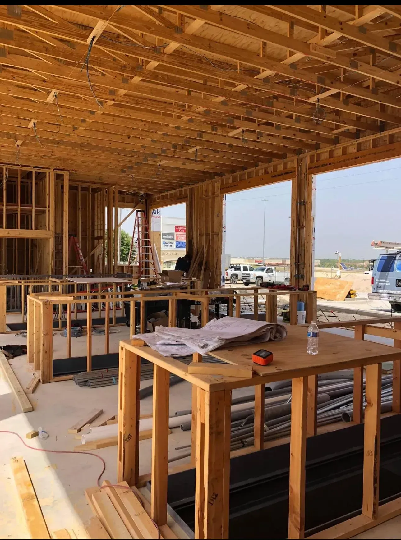 The inside of a building under construction with wooden tables and chairs.