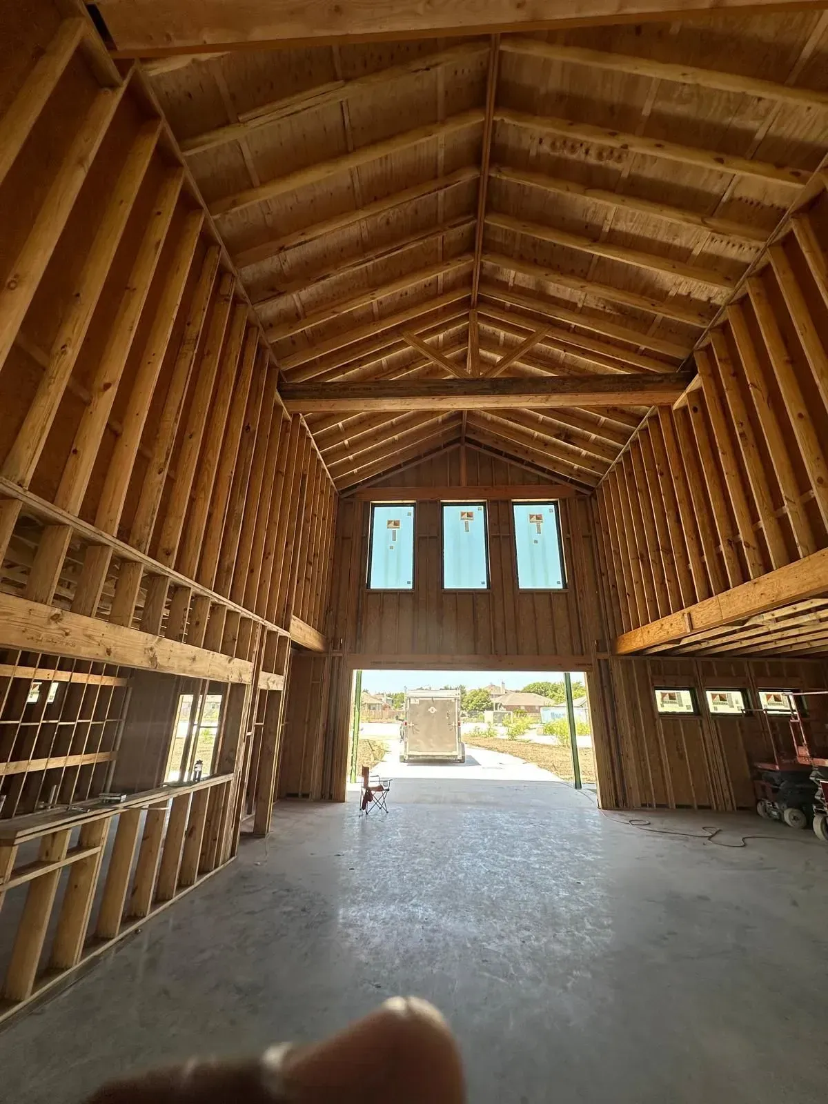 A person is taking a picture of the inside of a barn under construction.