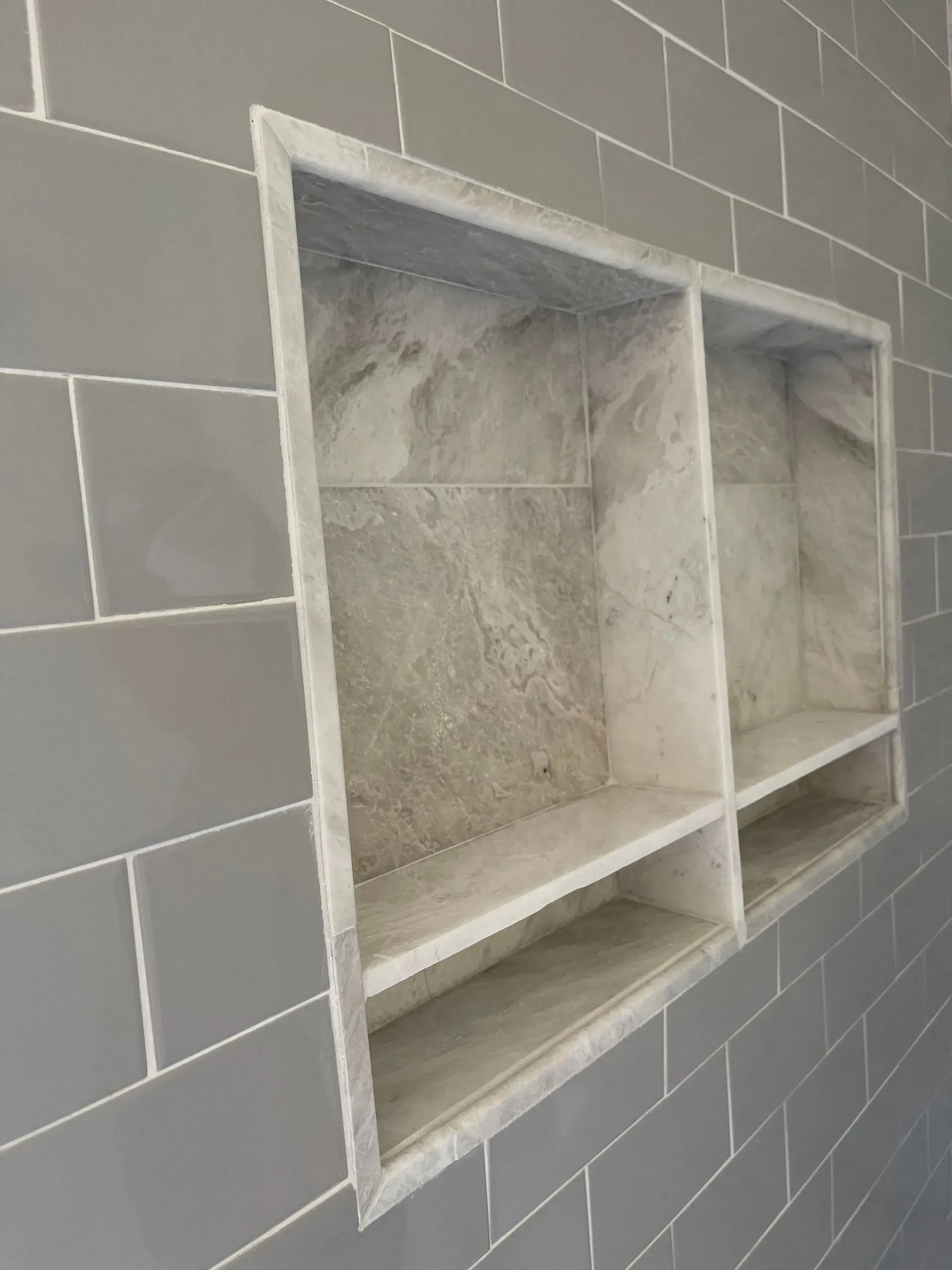 A bathroom with a built in shelf in the wall.