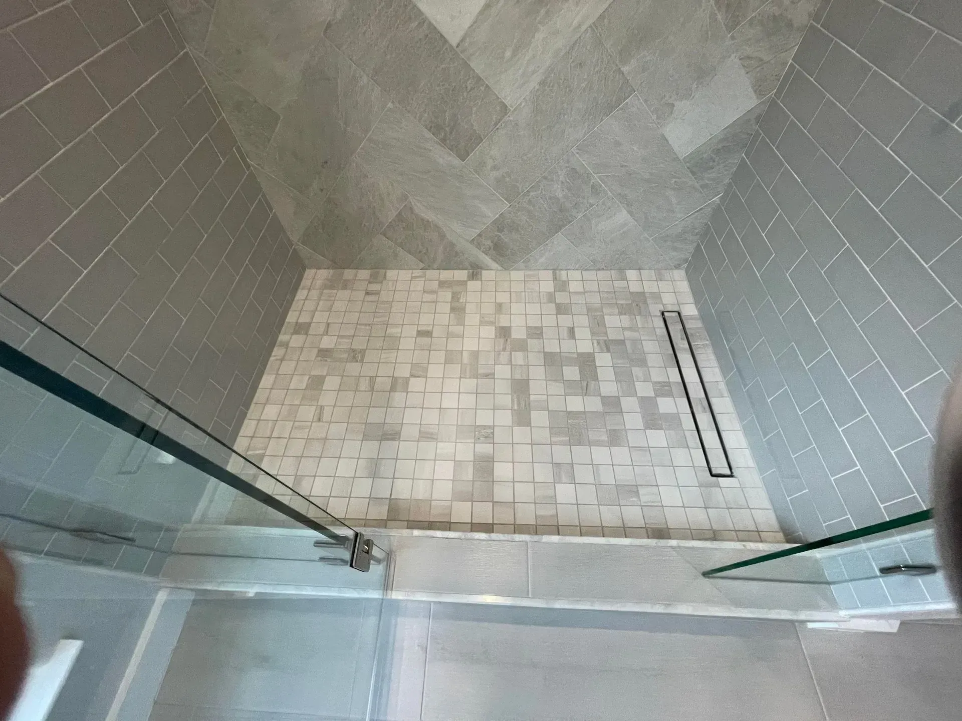 A bathroom with a walk in shower and a glass door.