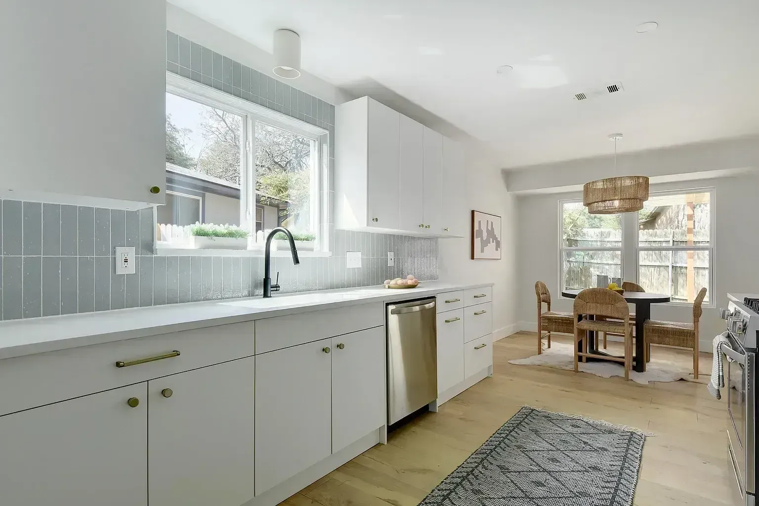 A kitchen with white cabinets , stainless steel appliances , and a rug.