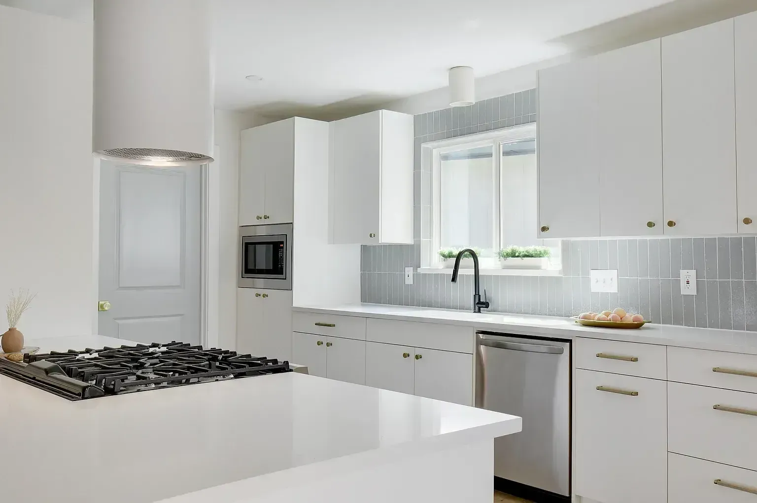 A kitchen with white cabinets , a stove top oven , a sink , and a window.