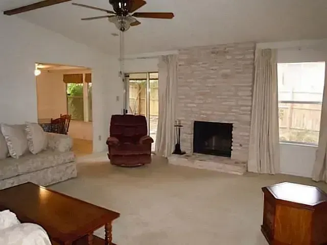 A living room with a fireplace and a ceiling fan