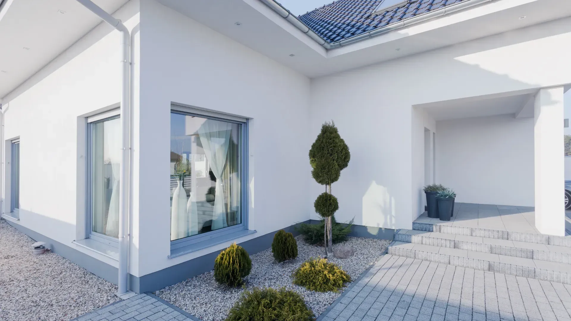 The front of a white house with a blue roof and a driveway.