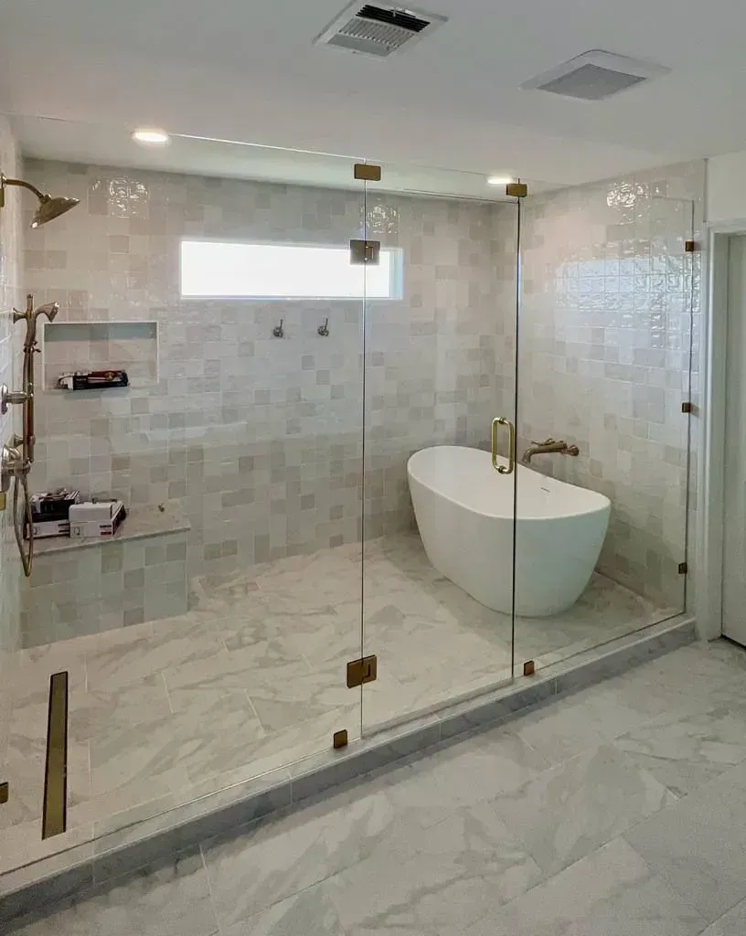 A bathroom with a bathtub and a walk in shower with glass doors.