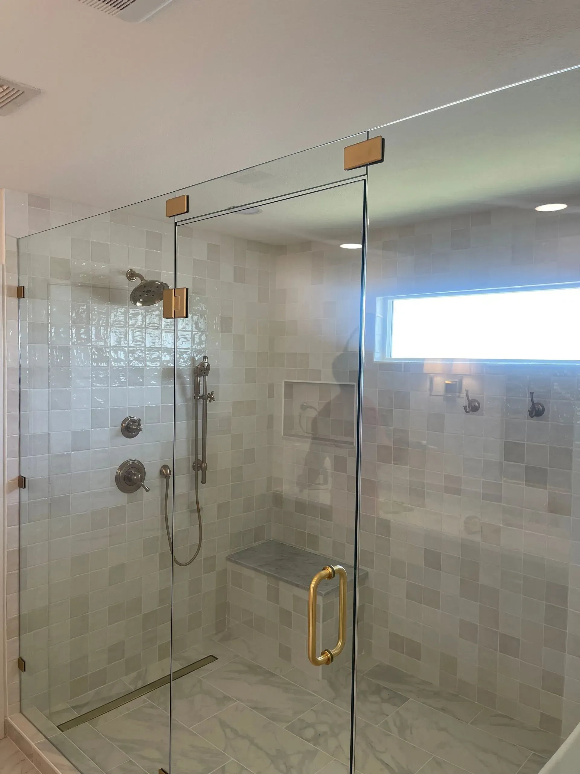A bathroom with a walk in shower with a glass door.