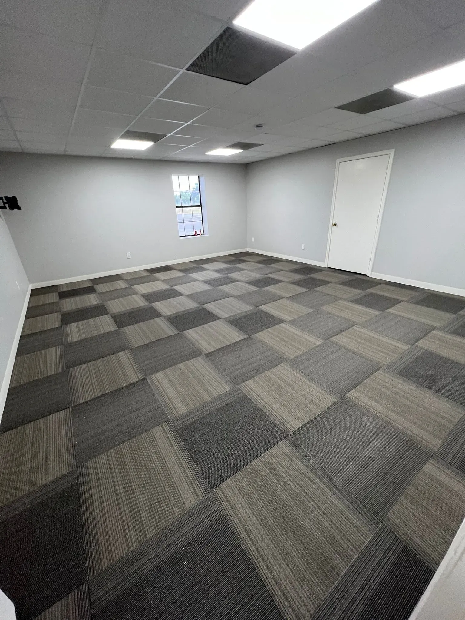 A large room with a checkered carpet and a window.