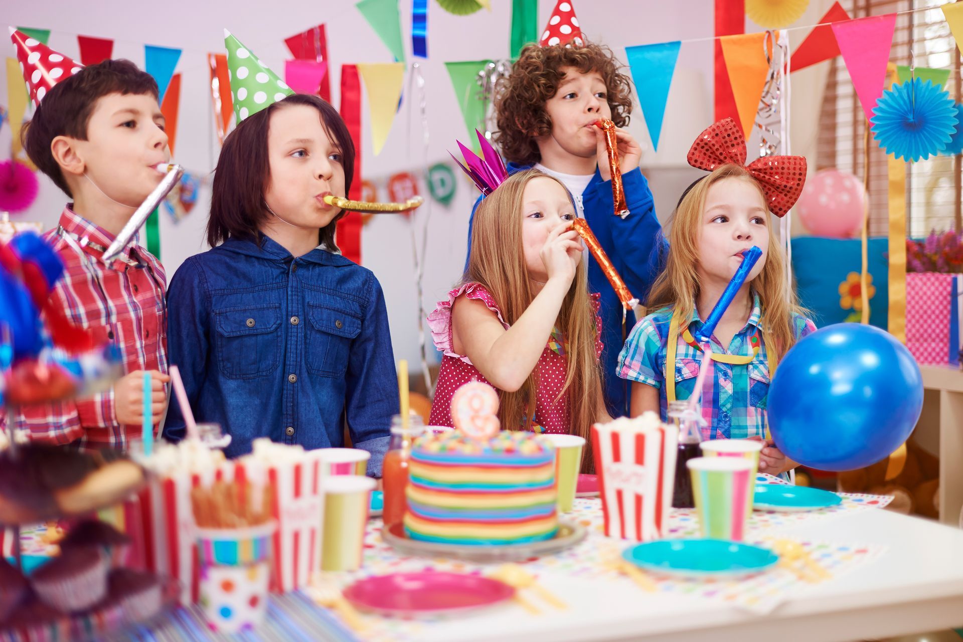 a group of children are blowing party horns at a birthday party .