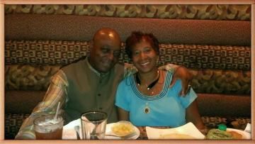 Two people smile while sitting together at a booth in a restaurant.