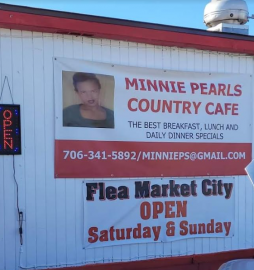 Exterior sign for Minnie Pearls Country Cafe and Flea Market City, featuring their contact info and business hours.