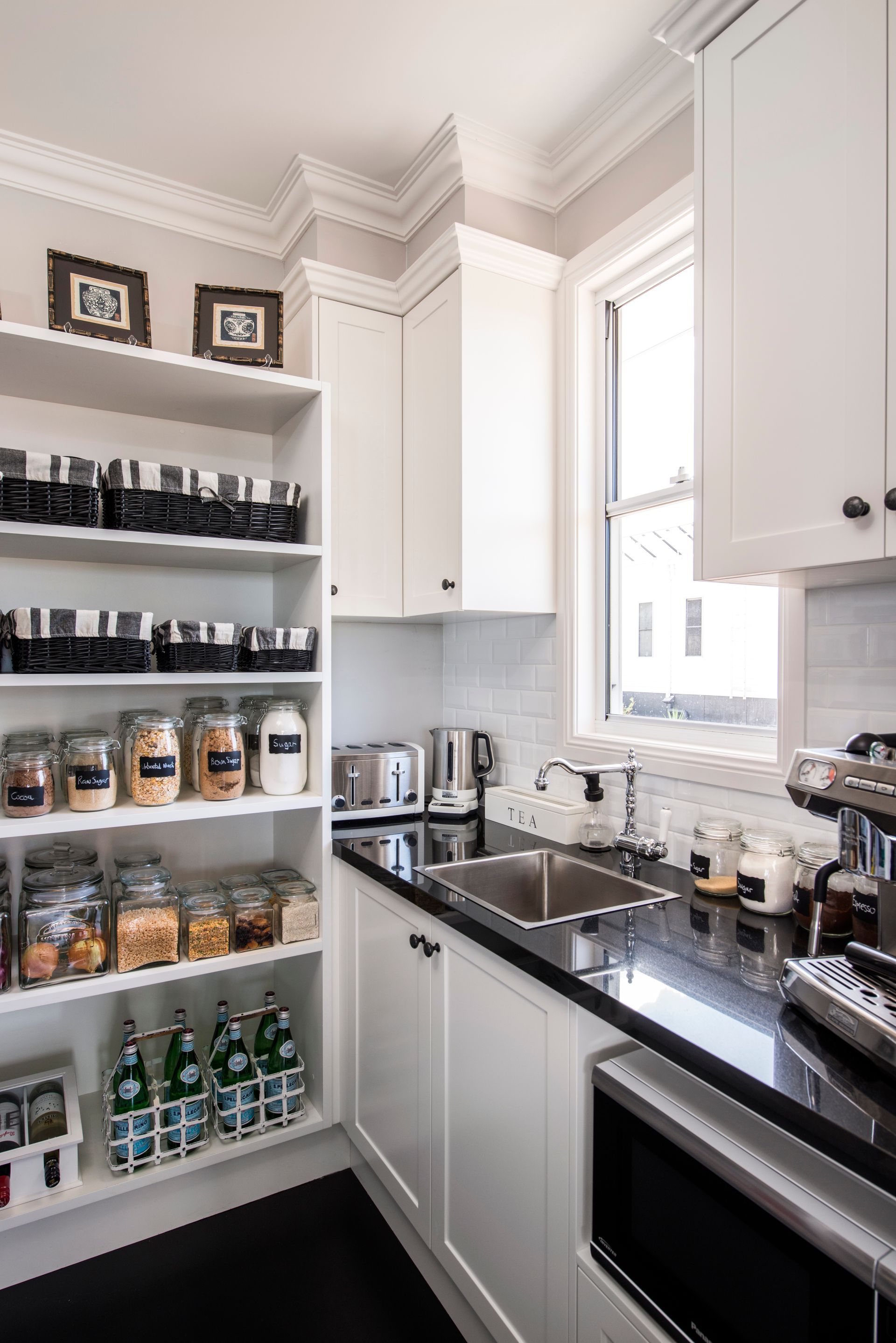 Modern kitchen with a large island, bar stools, dark cabinets, and wood floors in a bright room