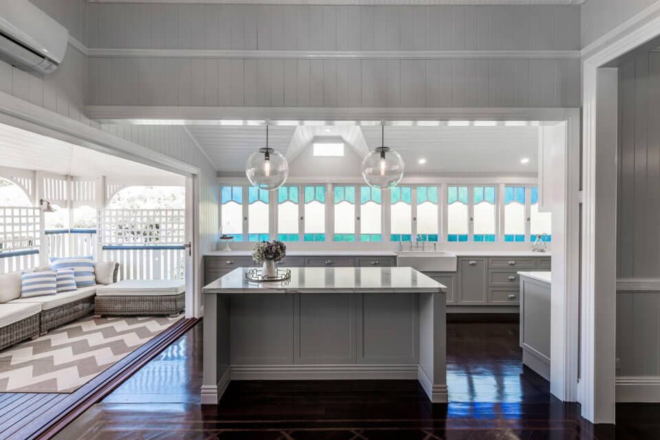 Bright white kitchen with central island, dark wood floors, and sunlit windows over the sink