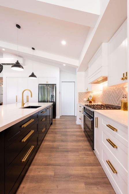Modern minimalist kitchen with dark cabinets, white island, and large windows overlooking a green backyard