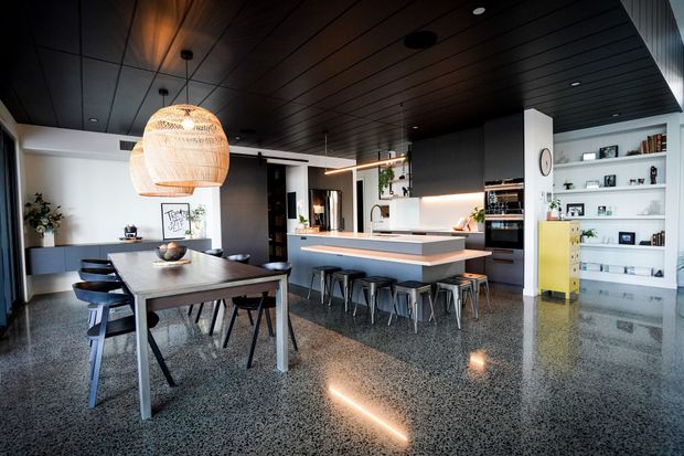 Modern kitchen with white cabinets, black island, pendant lights, and warm under-cabinet lighting.