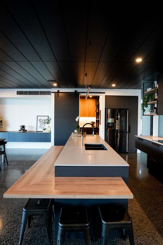 Modern kitchen with light wood cabinets, stone countertop, and built-in tall pantry cabinet