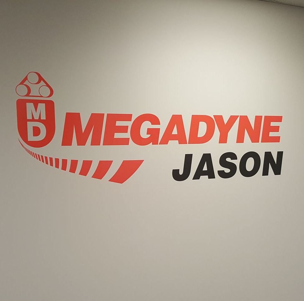 Megadyne Jason logo on a white wall: Red and black text, with a stylized conveyor belt graphic.