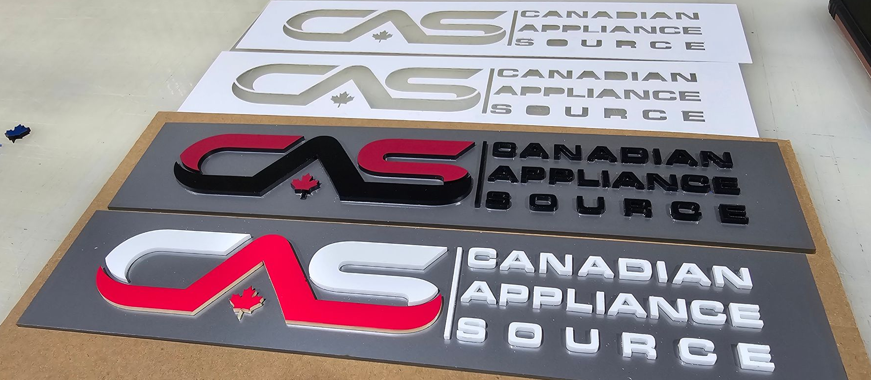 Plusieurs panneaux pour Canadian Appliance Source dans différentes combinaisons de couleurs sur une surface en bois.