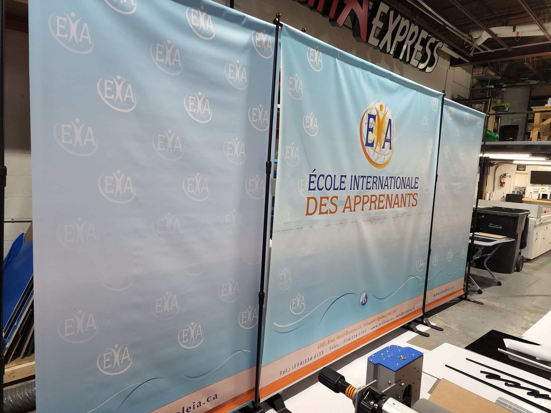 Banner for École Internationale des Apprenants, light blue with logo and text, set up indoors.