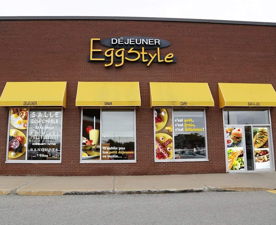 Extérieur du restaurant « Eggstyle » avec auvents jaunes et présentoirs de nourriture.