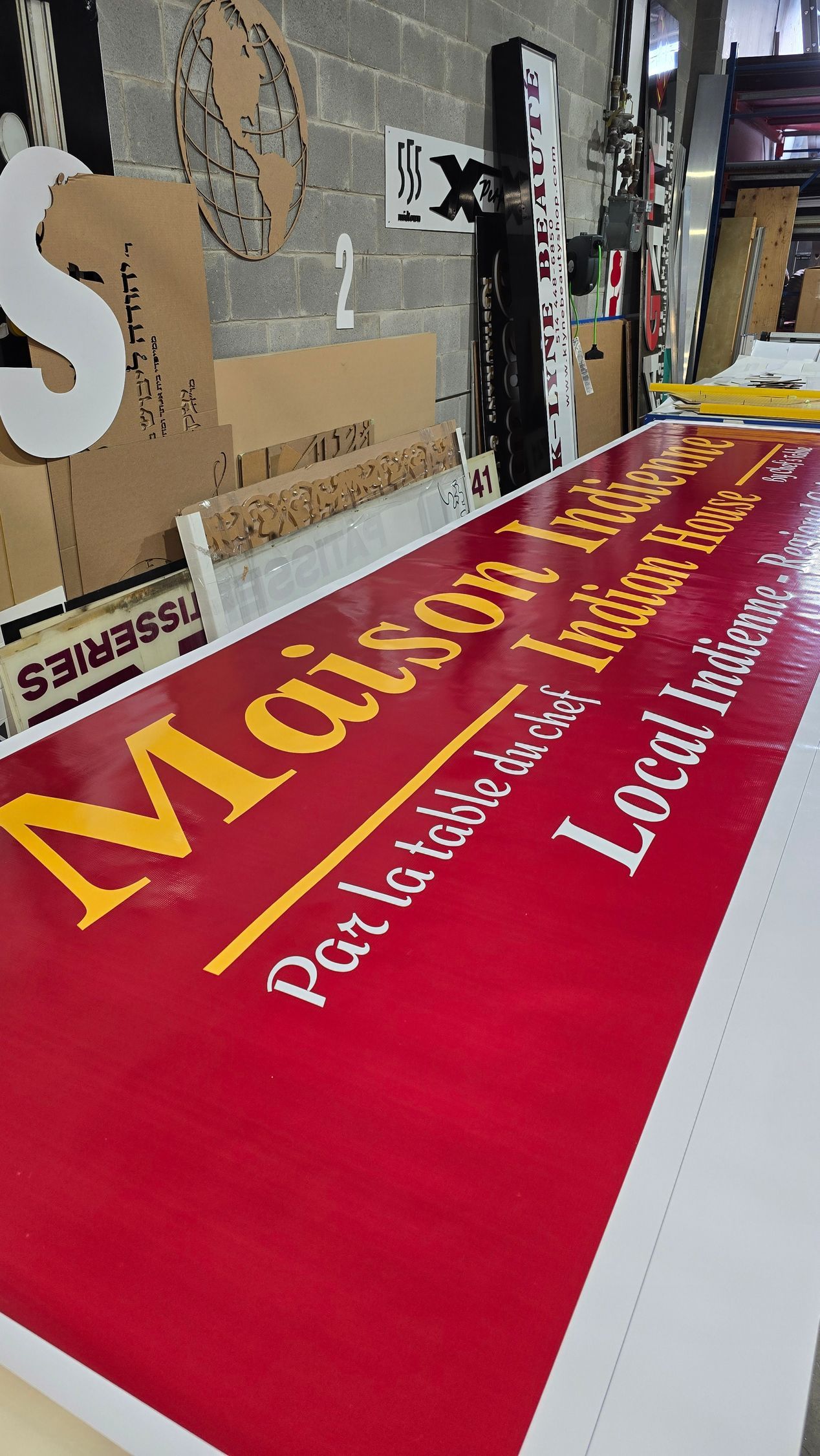 Panneau rouge avec texte jaune : « Maison Indienne » et « Local Indian ».