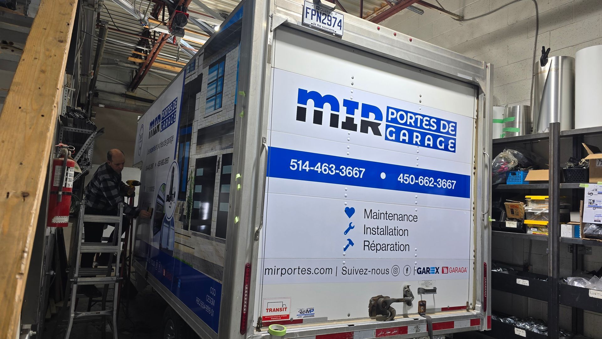 Fourgonnette Dodge blanche avec porte-échelle, logo de l'entreprise et coordonnées sur le côté et à l'arrière, garée à l'extérieur.