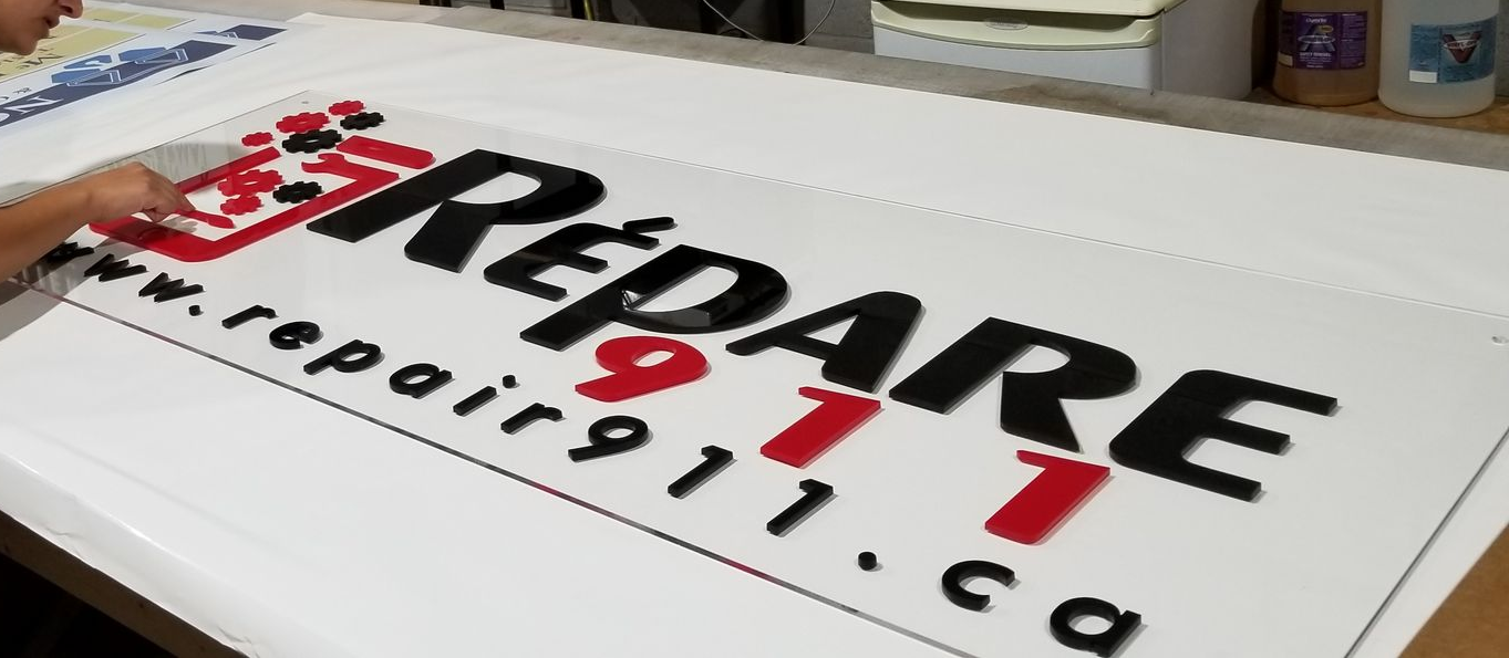 Personne appliquant un logo noir et rouge sur une bannière blanche pour repair911.ca.