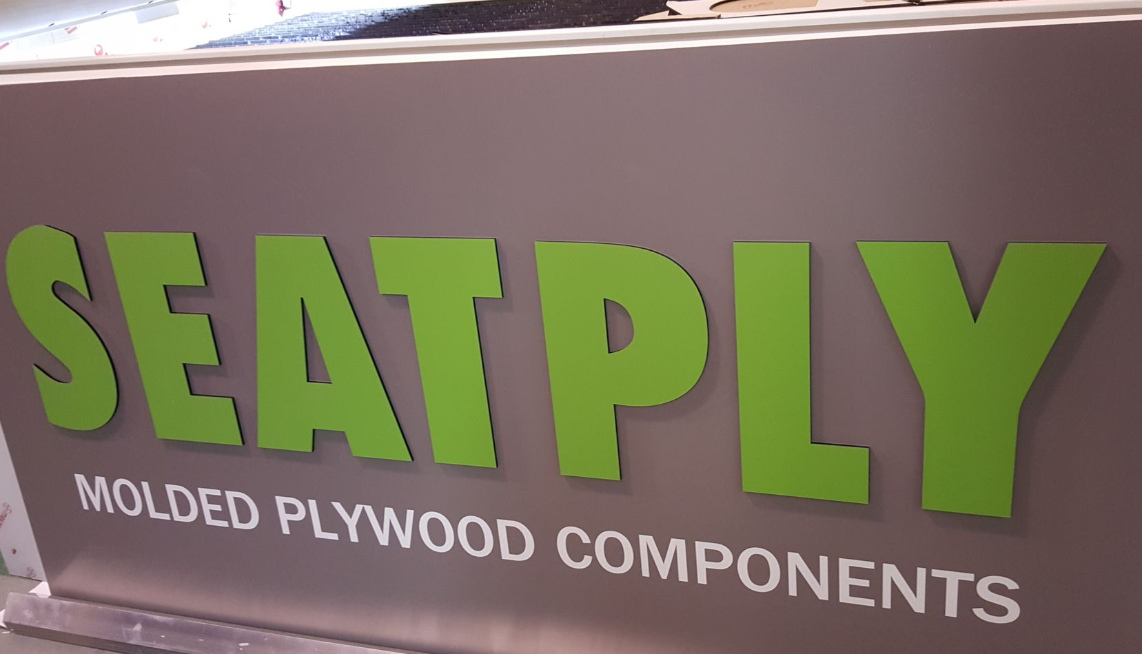 Panneau pour « SEATPLY » en vert sur fond gris, avec « COMPOSANTS EN CONTREPLAQUÉ MOULÉ » en dessous.