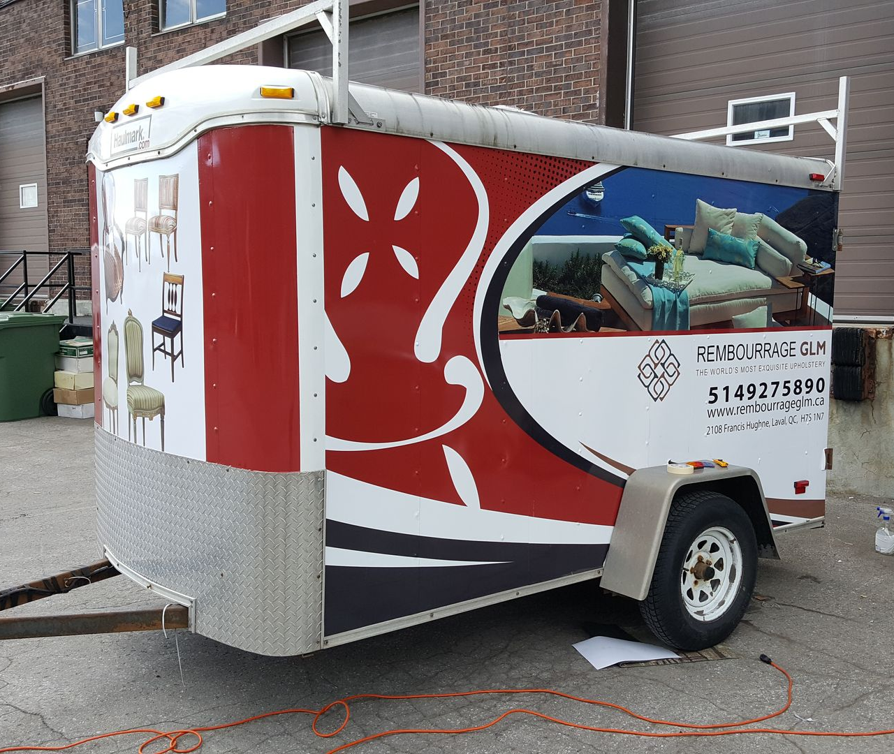 Remorque meuble avec graphisme rouge et blanc, stationnée à l'extérieur.