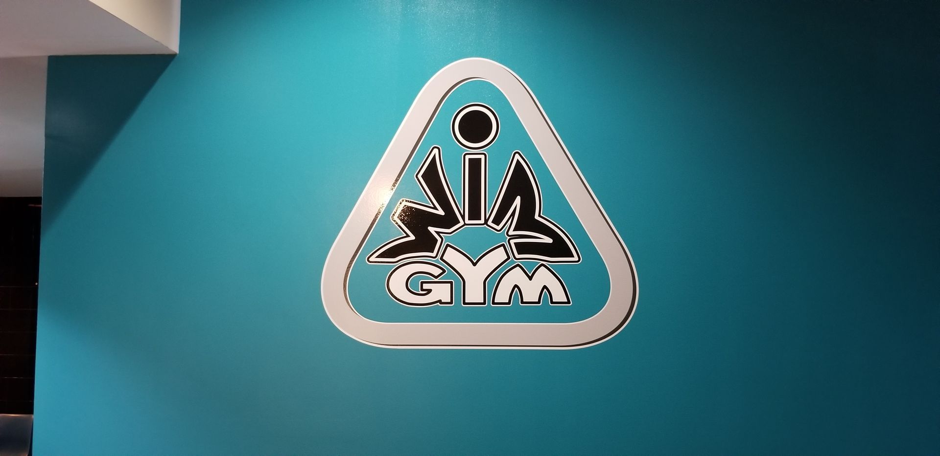Logo for SIA GYM on a blue wall.